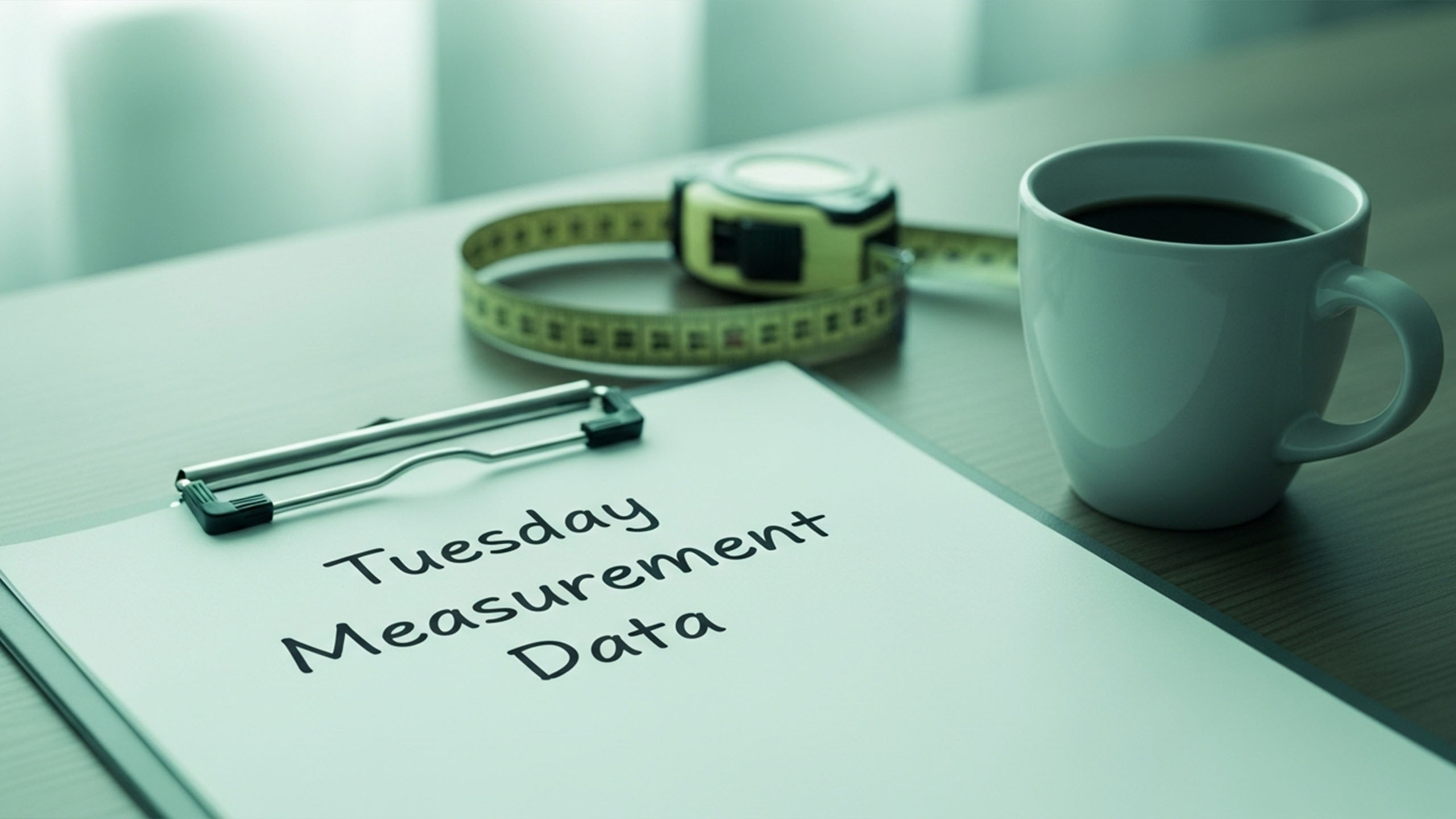Mock science setup with clipboard labeled “Tuesday Measurement Data,” tape measure, and calendar circled on Tuesday.