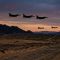 Military aircraft flying over a desert landscape during a strategic operation.