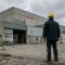 Canadian tradesman standing outside a warehouse beside a faded Now Hiring sign, representing the broken foreign worker hiring system