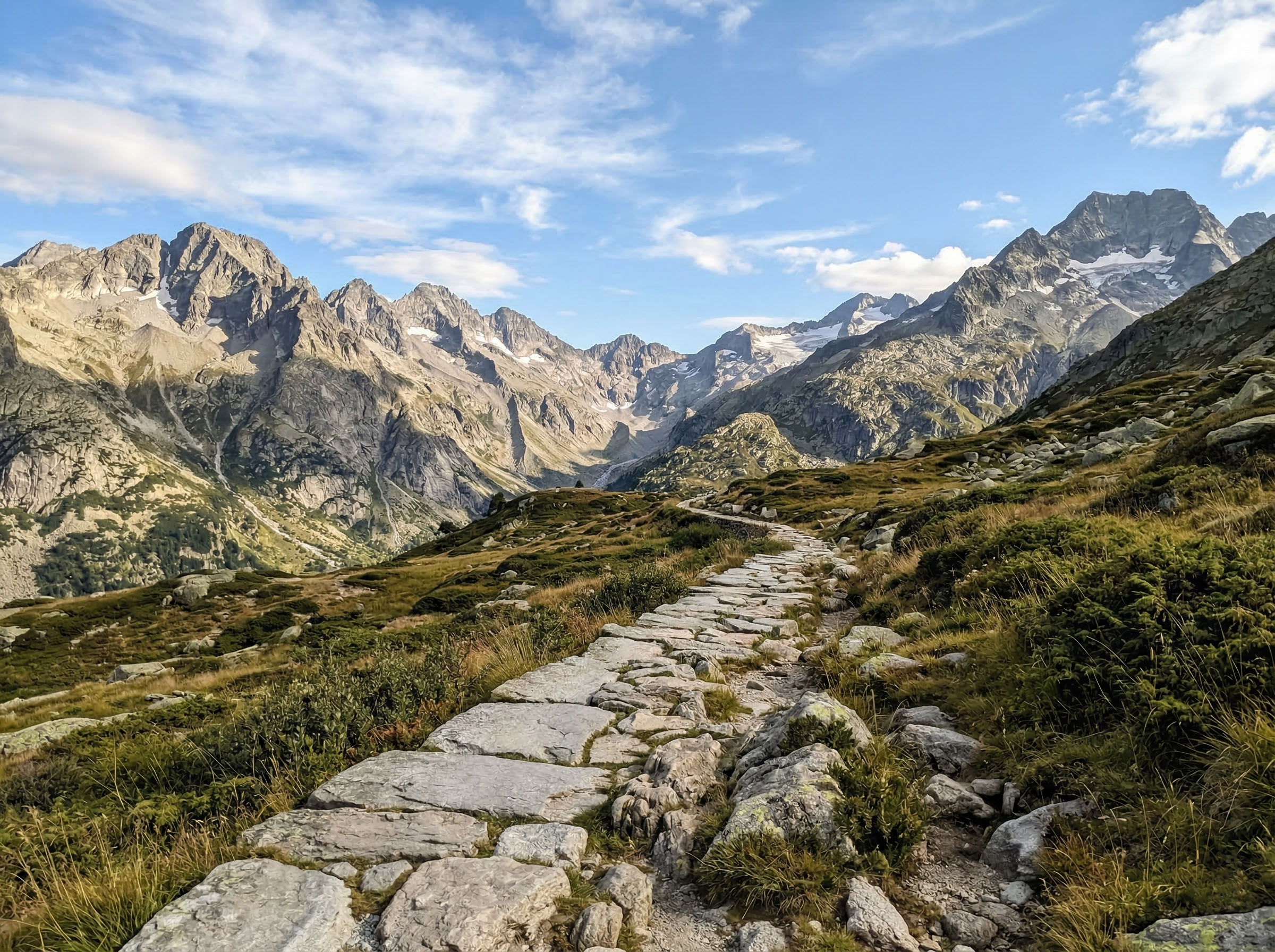 A clear stone path leading through a rugged mountain range