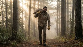 Un hombre demostrando fuerza funcional al cargar una pesada carga en un entorno natural.