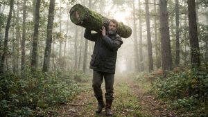 Un homme démontrant sa force fonctionnelle en portant une lourde charge en pleine nature.