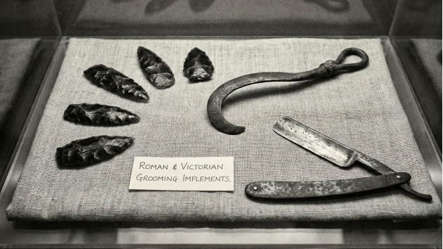 Colección de herramientas tradicionales y modernas para el cuidado masculino, incluyendo navaja y maquinilla de seguridad.