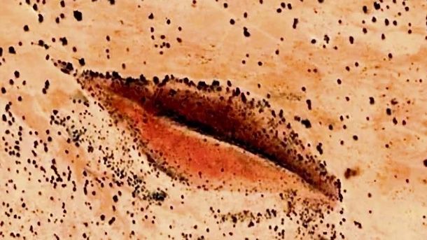 Sandsteinformation in der Darfur-Wüste, die der weiblichen Anatomie ähnelt, leuchtend im Sonnenuntergang.