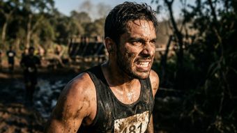 Homem competindo sozinho em um desafio físico exigente, incorporando o impulso bruto e a conquista merecida