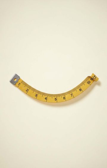 Vintage measuring tape curved into a smile, symbolizing humor and confidence