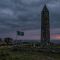 Torre de pedra irlandesa antiga sob céu tempestuoso, representando a herança irlandesa e o espírito celta