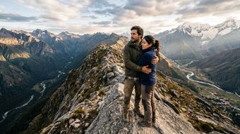 Un hombre y una mujer en una cima rocosa simbolizando unión pese a perspectivas distintas.