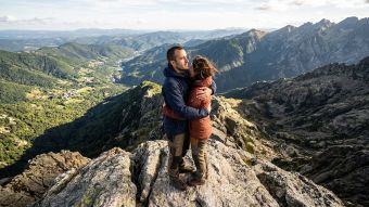Un homme et une femme sur un sommet rocheux, symbolisant un partenariat malgré des perspectives différentes.
