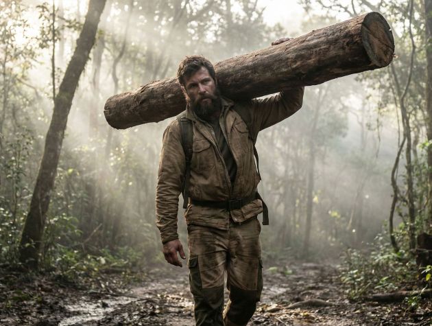 Um homem demonstrando força funcional carregando uma carga pesada em um ambiente natural.