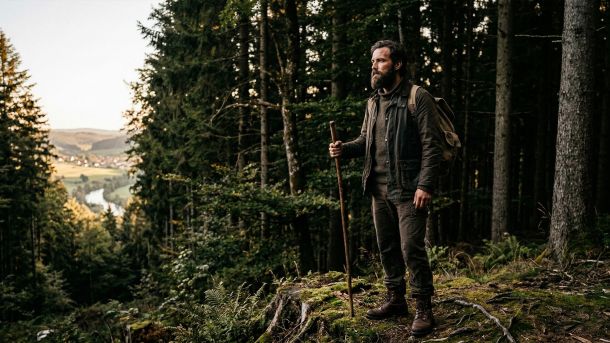 Ein entschlossener Mann blickt über ein Tal und symbolisiert männliche Gesundheit und generationelles Erbe.