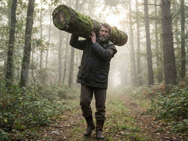 Un homme démontrant sa force fonctionnelle en portant une lourde charge en pleine nature.