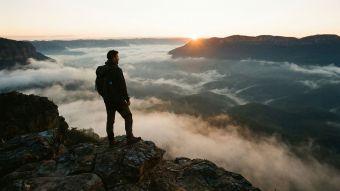 A man overlooks a rugged mountain landscape during a solo expedition.