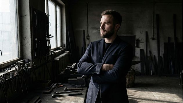 A confident man standing with strong posture and open body language.