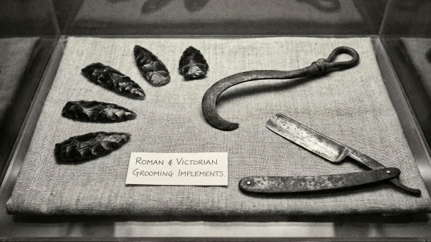 A collection of traditional and modern male grooming tools including a straight razor and safety razor.