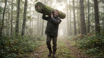 Un homme démontrant sa force fonctionnelle en portant une lourde charge en pleine nature.