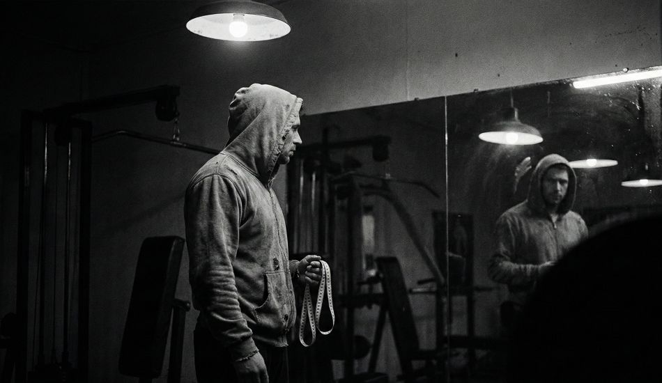 Un homme examinant son reflet, symbolisant la pression des statistiques physiques masculines.